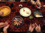 Tourists learn to make nigiri sushi with rice, top left, and slices of fish, as they prepare dinner at the home of Shino Fukuyama in Tokyo.