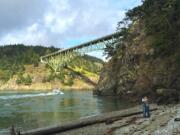 A couple embraces on North Beach with Deception Pass Bridge as a backdrop in Deception Pass State Park on Whidbey Island. Deception Pass, about 80 miles from Seattle, is the name of the strait that divides Washington&#039;s Whidbey Island from Fidalgo Island.