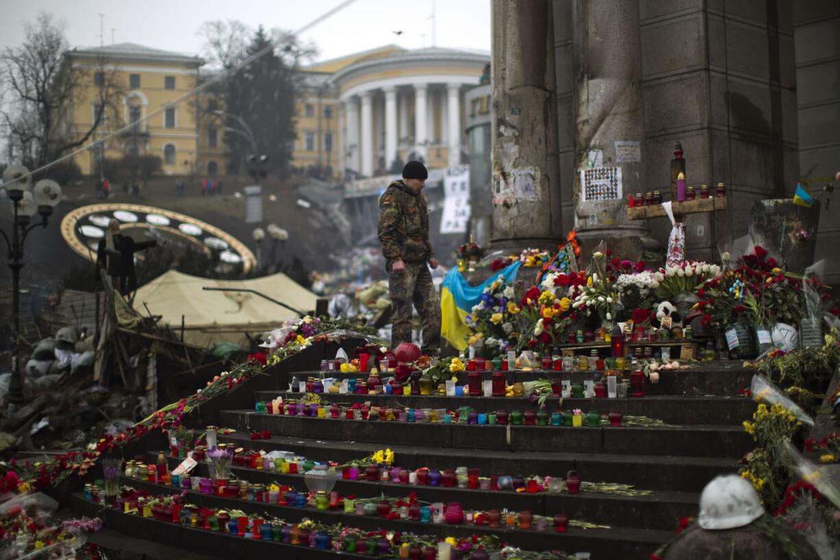 An anti-Yanukovych protester stands at a memorial for the people killed in clashes with the police at Kiev's Independence Square, the epicenter of the country's current unrest, on Saturday.