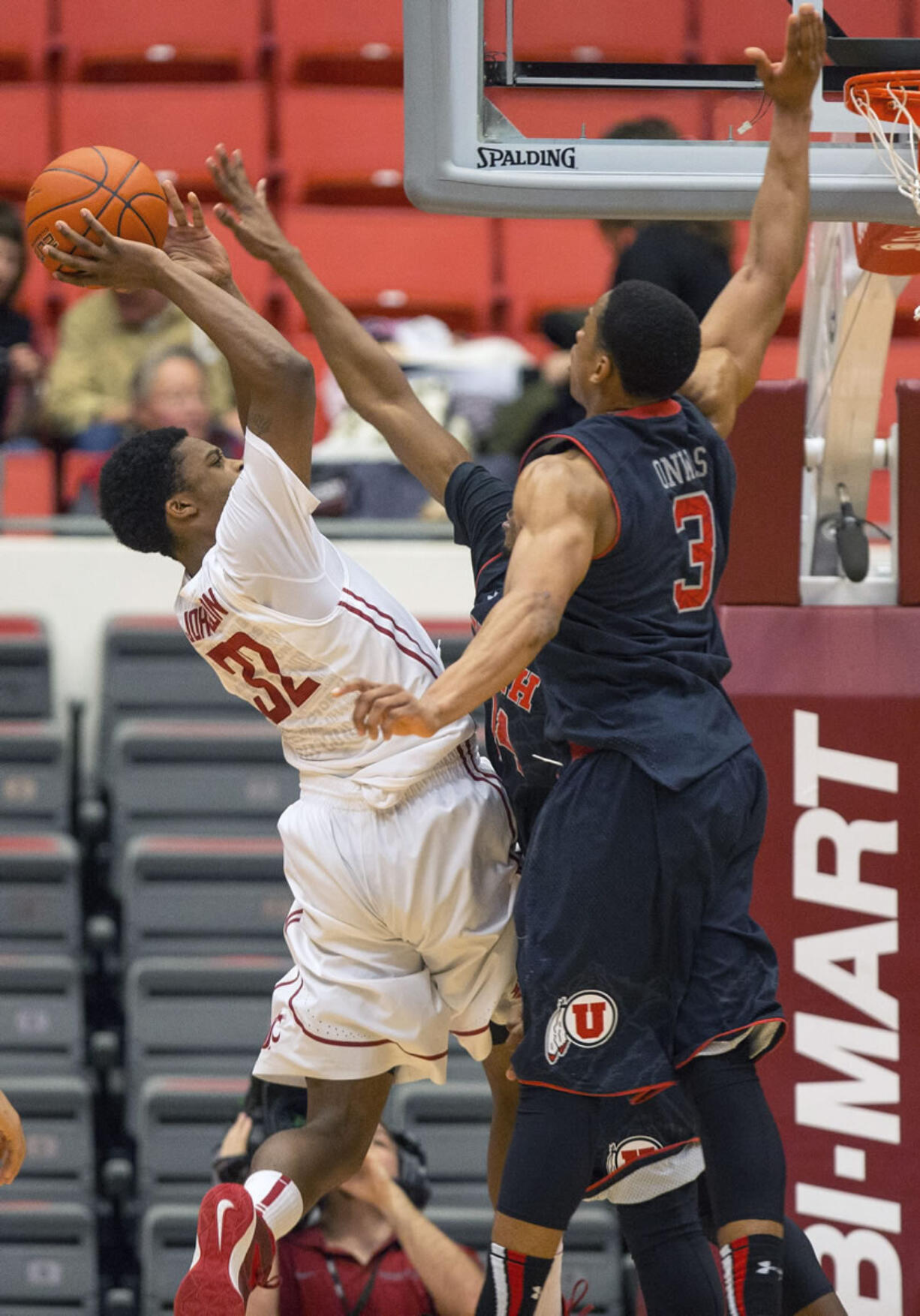 Washington State guard Que Johnson (32) scores and draws a foul on the shot over Utah guard Dakarai Tucker, obscured, as guard Princeton Onwas (3) helps defend during the second half Sunday at Pullman. Johnson lead Washington State with 14 points at they won 49-46.