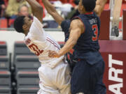 Washington State guard Que Johnson (32) scores and draws a foul on the shot over Utah guard Dakarai Tucker, obscured, as guard Princeton Onwas (3) helps defend during the second half Sunday at Pullman. Johnson lead Washington State with 14 points at they won 49-46.