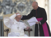 Pope Francis is helped by his personal secretary Mons. Alfred Xuereb, right, with his skull cap during a gust of wind while he attends his weekly open-air general audience in St. Peter's Square at the Vatican in May.