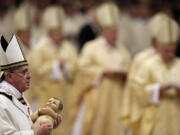 Pope Francis carries a statue of baby Jesus as he celebrates the Christmas Eve Mass on Tuesday in St.