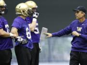 New Washington head football coach Chris Petersen, right, talks to players on the first day of Spring NCAA college football practice, Tuesday, March 4, 2014 in Seattle. (AP Photo/Ted S.