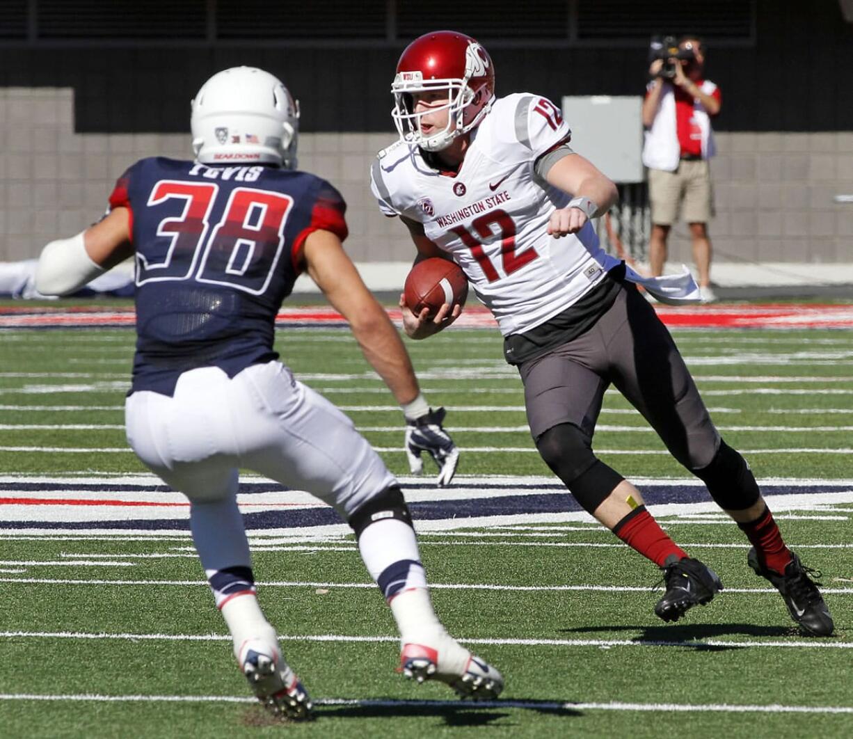 Washington State's quarterback Connor Holiday (12) runs for a short gain before being tackled by Arizona's Jared Tevis (38) in the first half of an NCAA college football game on Saturday, Nov. 16, 2013, in Tucson, Ariz.