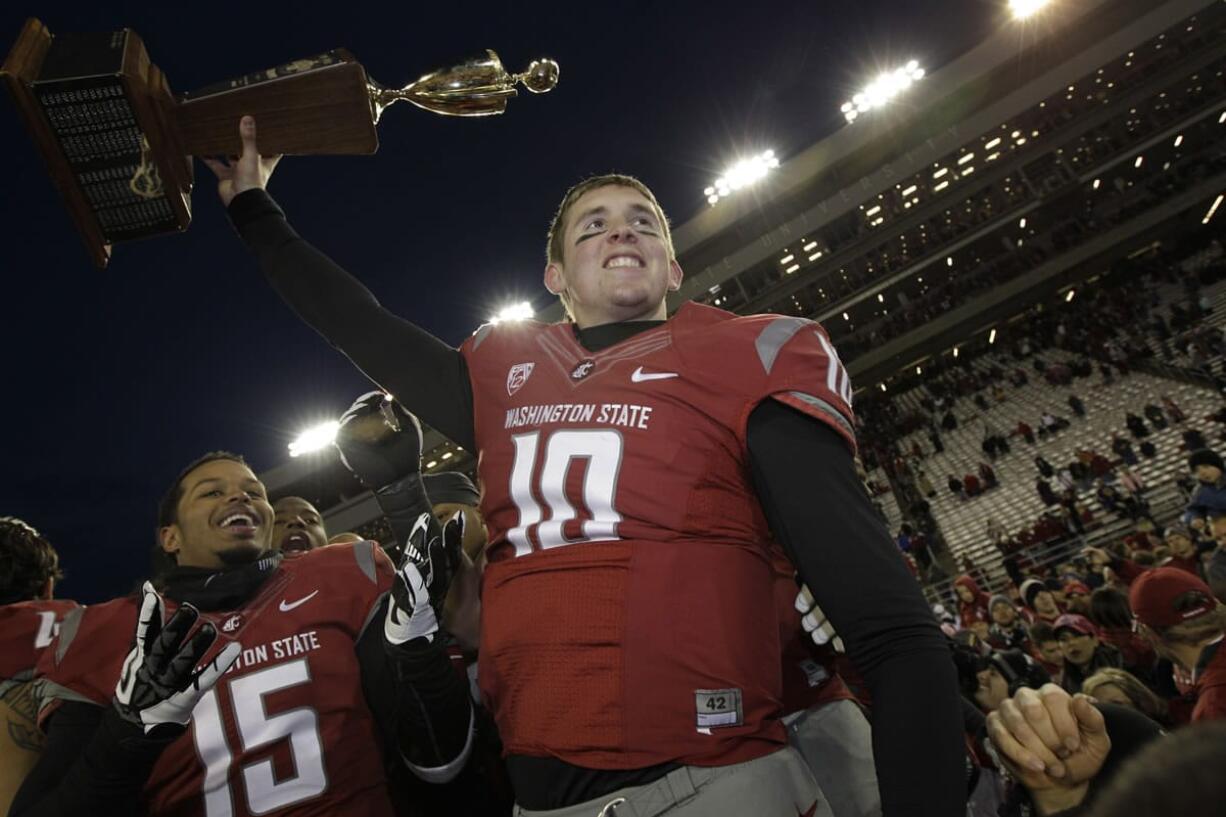 Washington State quarterback Jeff Tuel lifts the Apple Cup trophy as he celebrates with Tyree Toomer, left, after they defeated Washington 31-28 in overtime on Nov.