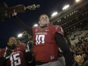 Washington State quarterback Jeff Tuel lifts the Apple Cup trophy as he celebrates with Tyree Toomer, left, after they defeated Washington 31-28 in overtime on Nov.