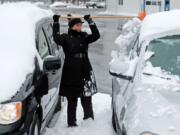 Kamila Pelliccia, a sales consultant at Don Mallon Chevrolet in Norwich, Conn., clears snow off vehicles in the dealership lot Wednesday.