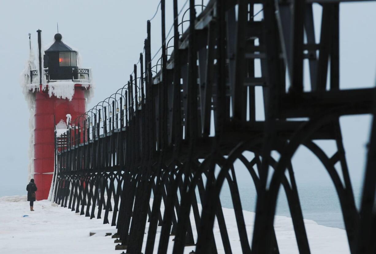 A woman explores an ice-covered pier at the South Haven Lighthouse Saturday in South Haven, Mich.