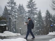 Anthropology major Daniel Radcliffe, 31, carries a stack of book across the Washington State University Vancouver campus Monday. The campus reopened at 11 a.m.