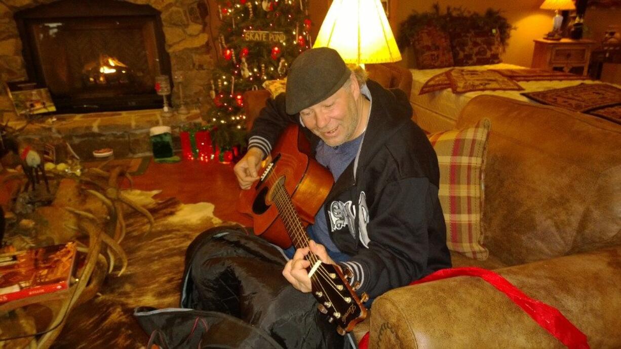 Buddy Carr Jr., who is homeless, strums a guitar given to him on Christmas at Cabin Fever Log Furniture in Kalama. Store owner Donna Bergeron not only gave Carr that present, but has supported him with food and lodging since meeting him in early December.