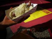 Anjelica Bautista, 16, of Vancouver, grabs her sausage with sauerkraut at the Sausage Fest at St. Joseph's Catholic School in 2013.