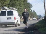 A pedestrian walks on a dirt path in the glass along Southeast First Street in east Vancouver last month.