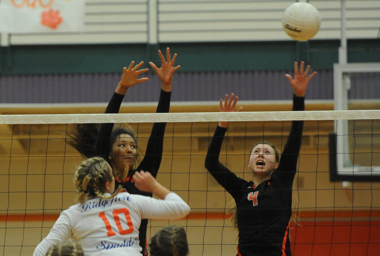 Battle Ground High School's "Lady Tigers" Ashley Watkins (C) and Kimberly Lasley (R) defend the net against Ridgefield's Madi Harter (L) at a volleyball in Battle Ground Thursday September 10, 2015.