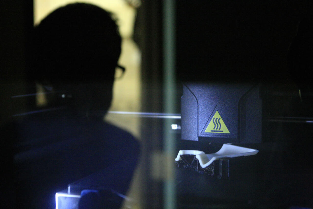 Benjamin Dolan, director of design and engineering research projects at RapidTech, operates a three-dimensional printer to a plastic airplane part in Irvine, Calif.