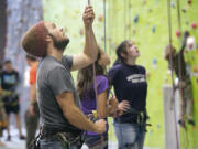 Bryan Caldwell, a climbing instructor at The Source Climbing Center, belays as a student climbs a wall during a class in October.