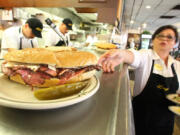 Sheila Abramson, a waitress at Langer's Delicatessen in Los Angeles, reaches out for a plate while serving customers on National Pastrami Day on January 14.