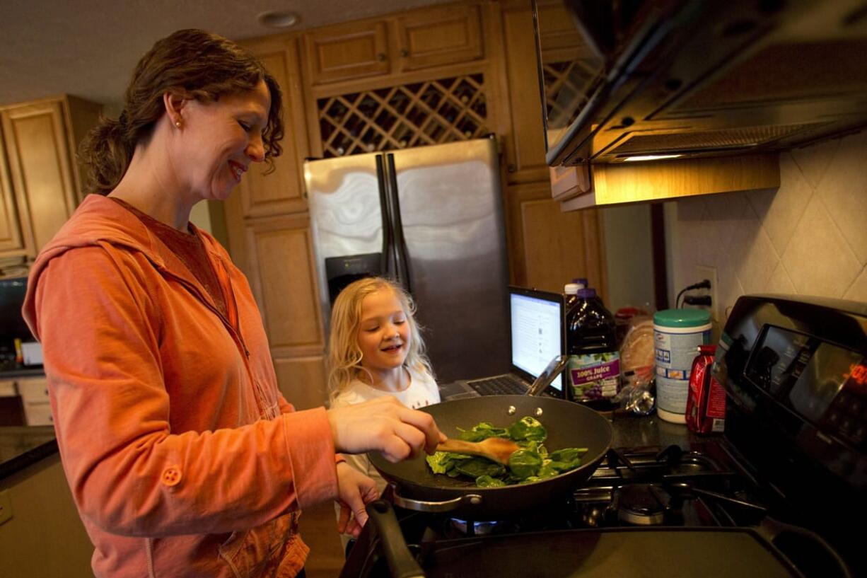 Sara Baker cooks dinner with her daughter Megan at their home in Bloomington, Ill.