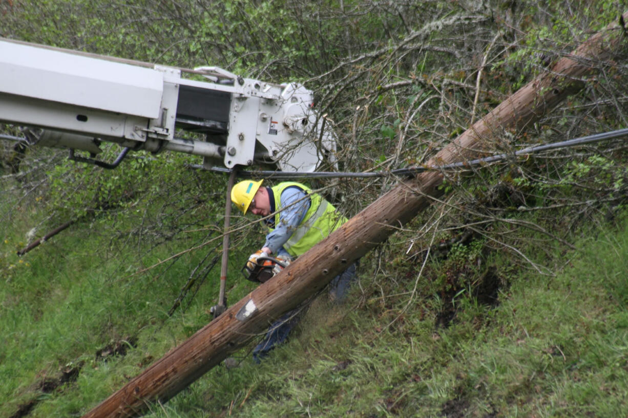 A crew member cuts down a damaged telephone pole at Milepost 21 on westbound State Route 14.