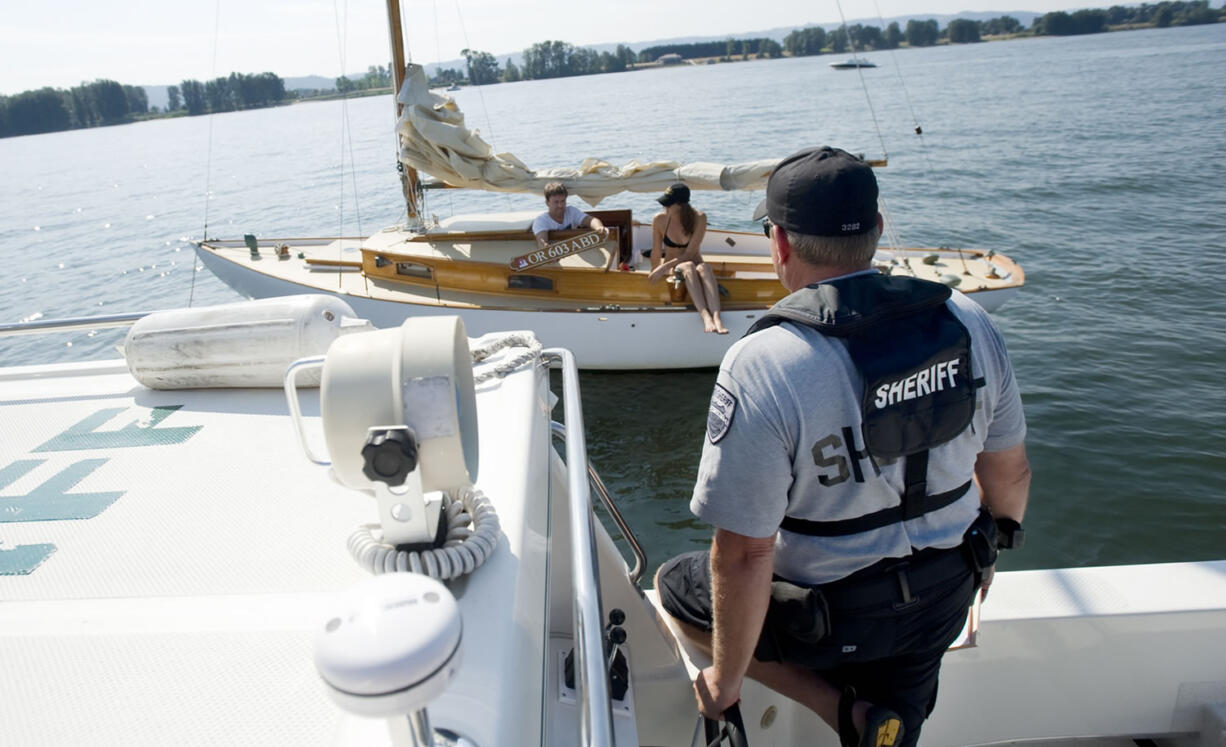 Clark County Sheriff's Deputy Todd Baker talks with boaters in August 2011 about missing registration numbers on a sailboat they were using for the day.