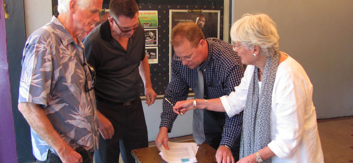 Rand Thornsley (second from left), managing director of The Rootstock Capital Management LLC, prepares to sign a five-year lease with Gary and Marilyn Webberley, owners of the Liberty building through Fourth Avenue Liberty LLC. Greg Goforth (second from right), a commercial real estate broker with Coldwell Banker Commercial, Jenkins &amp; Associates, represented both parties. Thornsley plans to offer 3D presentations this summer and open an ice cream and sandwich shop next to the theater in July. He hopes to apply for a beer and wine license in June and start serving by Oct. 1.