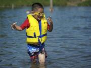 Esteban Cervantes, of Vancouver, wears a life vest while swimming at Klineline Pond in July 2012.