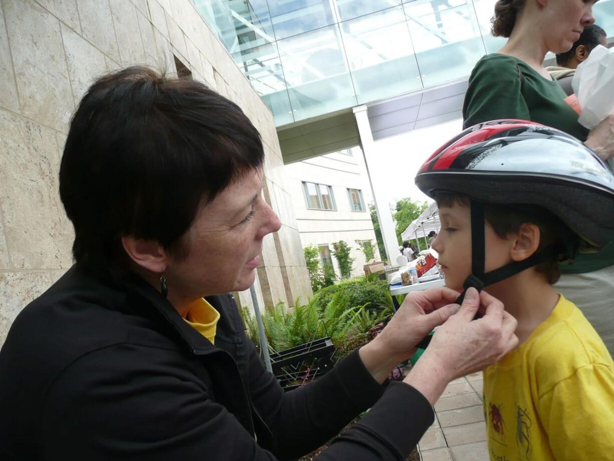 Debbie Mansell, a Legacy Salmon Creek Medical Center employee, fits a bicycle helmet during last year's annual Healthy Kids Fair.