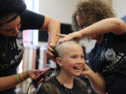 Washougal third-grader and cancer survivor Sammy Mederos reacts to getting her long locks of curly blond hair shaved off by Shelby Cummings (left) and Holly Thorpe (right) during a fundraiser for the St. Baldrick's Foundation Sunday at Washougal High School. Mederos was diagnosed with leukemia when she was in kindergarten. Now cancer-free, she and her parents, Michele and Dennis Mederos, helped organize the event.