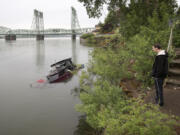 Michael Cole of Vancouver stops to look at a partially submerged boat. The boat has remained at the shoreline of Waterfront Park for more than a month.