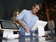 Matt Schodorf, owner of Schodorf's Luncheonette, swipes a credit card on the Square Stand at his restaurant June 5 in the Highland Park area of Los Angeles.