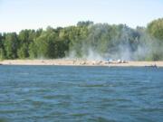 Beachgoers fight a grass fire that ignited on Bachelor Island on Thursday evening in Ridgefield.