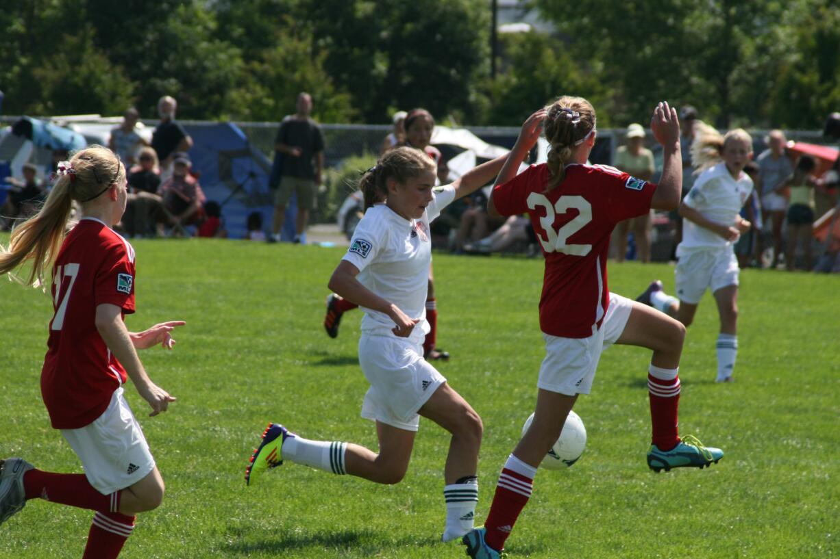 Perri Belzer (left) of the Vancouver Timbers 99 Red takes on a defender from the Camas-Washougal Soccer Alliance Valencia in the U-13 Platinum championship game of the Clash at the Border tournament.