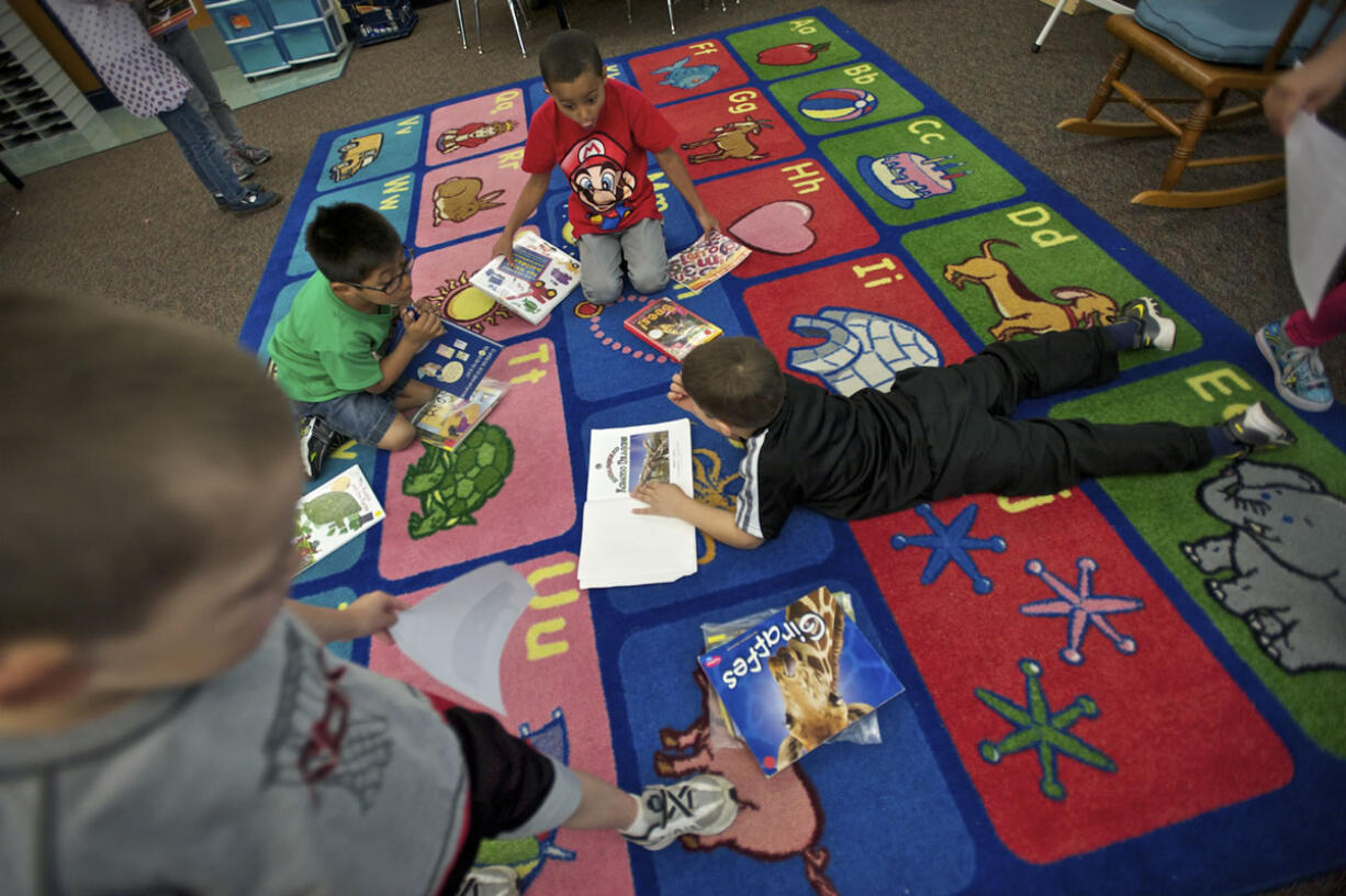 Kindergartners, from left,  Angel Rojas, 6, Damarian Walden, 6, and Steven Stempien, 6, read a book on a carpet inside Wayne Mason's class at Endeavour Elementary in May.