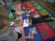 Kindergartners, from left,  Angel Rojas, 6, Damarian Walden, 6, and Steven Stempien, 6, read a book on a carpet inside Wayne Mason's class at Endeavour Elementary in May.