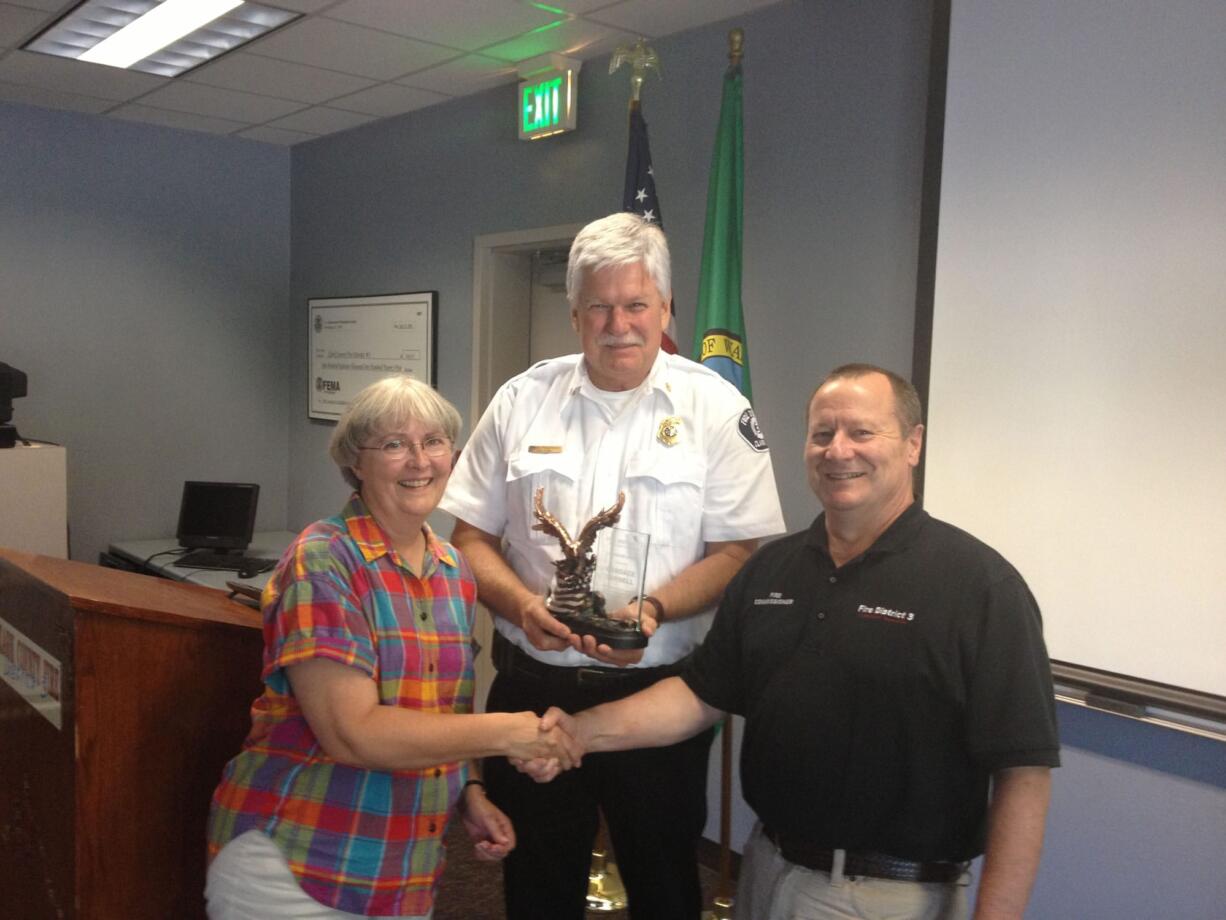 Fire District 3 Chief Steve Wrightson and Fire Commissioner Buck Heidrick present Candy Yarnell with a Lifesaving Award for successfully performing CPR on her husband, whose heart had stopped.