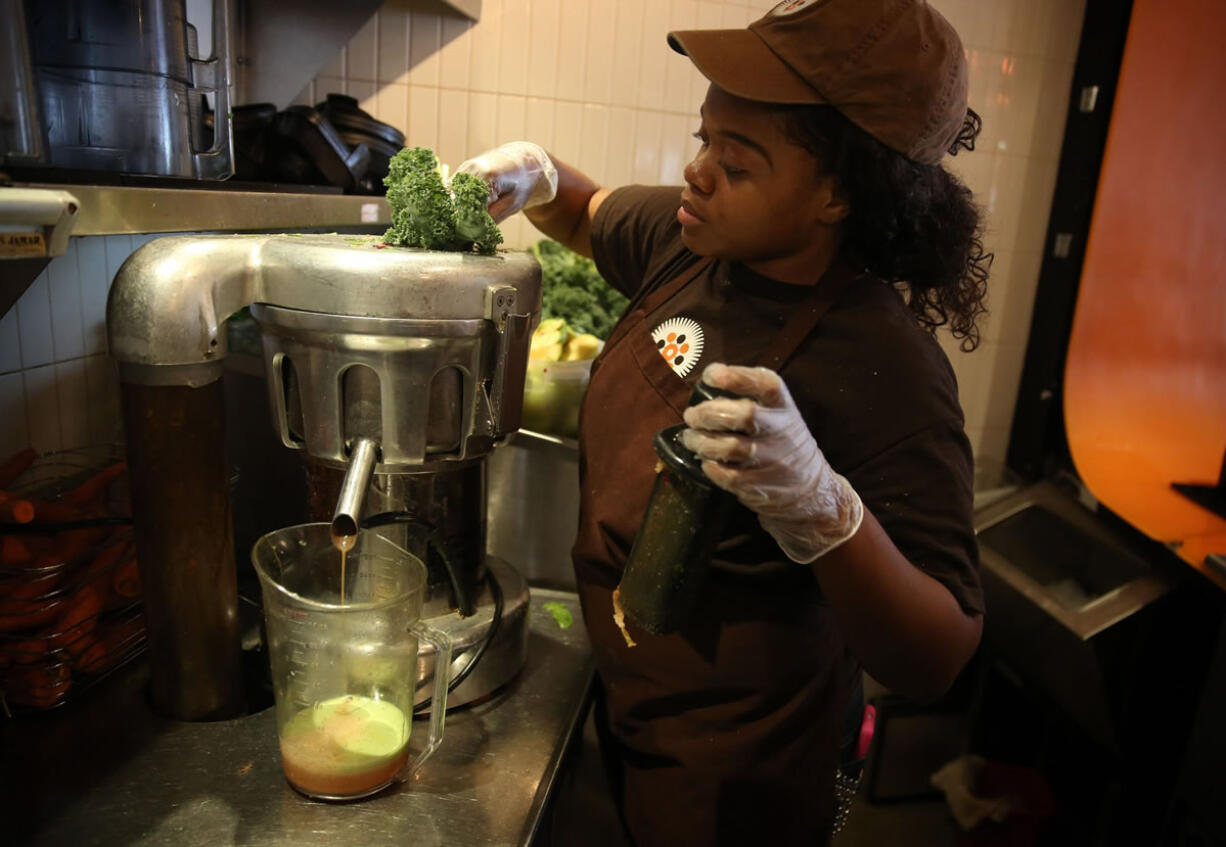 Kyra Scott loads kale into a juicer at Protein Bar in Chicago.