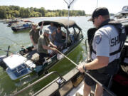 Todd Baker of the Clark County Sheriff's Office marine patrol hands paperwork back to a boat of anglers anchored near the shipping channel at the mouth of the Lewis River.