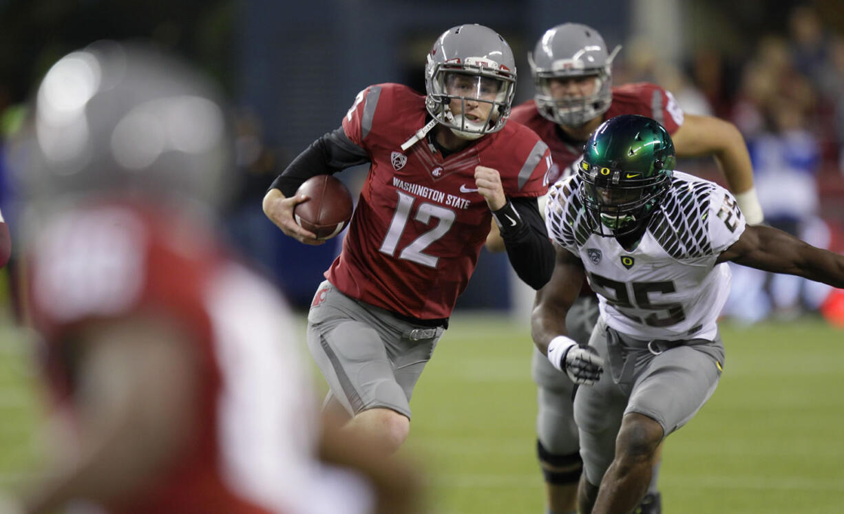 Washington State quarterback Connor Halliday scrambles with the ball as Oregon's Boseko Lokombo pursues in the second half of a game last season.