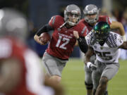 Washington State quarterback Connor Halliday scrambles with the ball as Oregon's Boseko Lokombo pursues in the second half of a game last season.