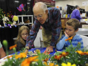 Clark County fairgoers Summer McNamara, left, with Hunter McNamara, right, listen to master gardener Bert Coffman talking about growing edible plants at the WSU Master Gardener exhibit.