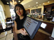 Marie Jose Brau, owner of the Bakery of France in Boca Raton, Fla., displays one of the iPad minis equipped with a Square credit card reader that her servers deliver to diners.