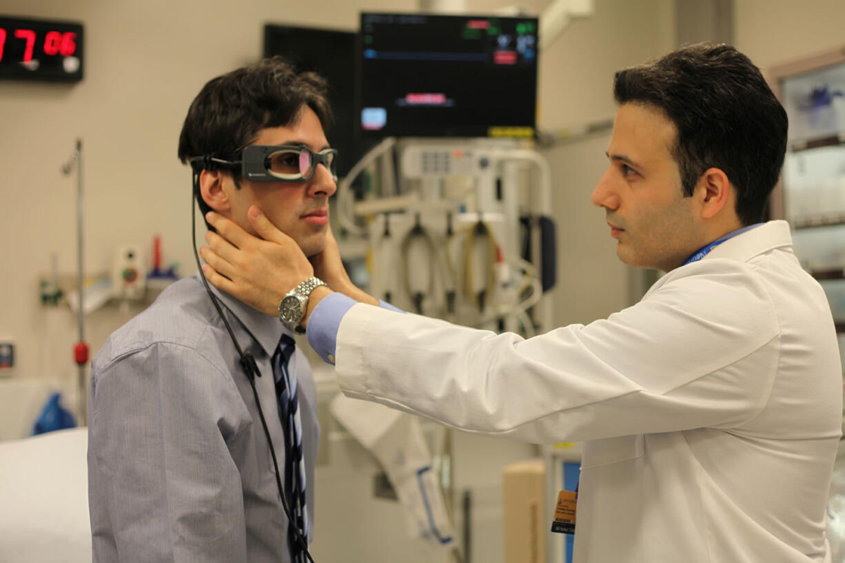 Johns Hopkins physicians Georglos Mantokoudis, left, and Ali Tehrani demonstrate the use of eye-tracking goggles that may replace expensive scans to determine if a person's dizziness is caused by an inner-ear infection or a stroke.