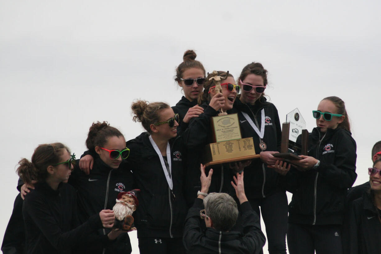 Members of the Camas High School girls cross country team grab hold of their state championship trophies.