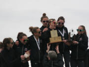 Members of the Camas High School girls cross country team grab hold of their state championship trophies.