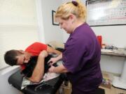 Chris Oldt, with Blue Ridge Veterinary Blood Bank in Loudoun County, Va., lays with Kenzie, a 5-year-old Newfoundland, as Dr. Valerie Latchford, veterinarian with Blue Ridge, injects a needle into Kenzie's jugular vein.