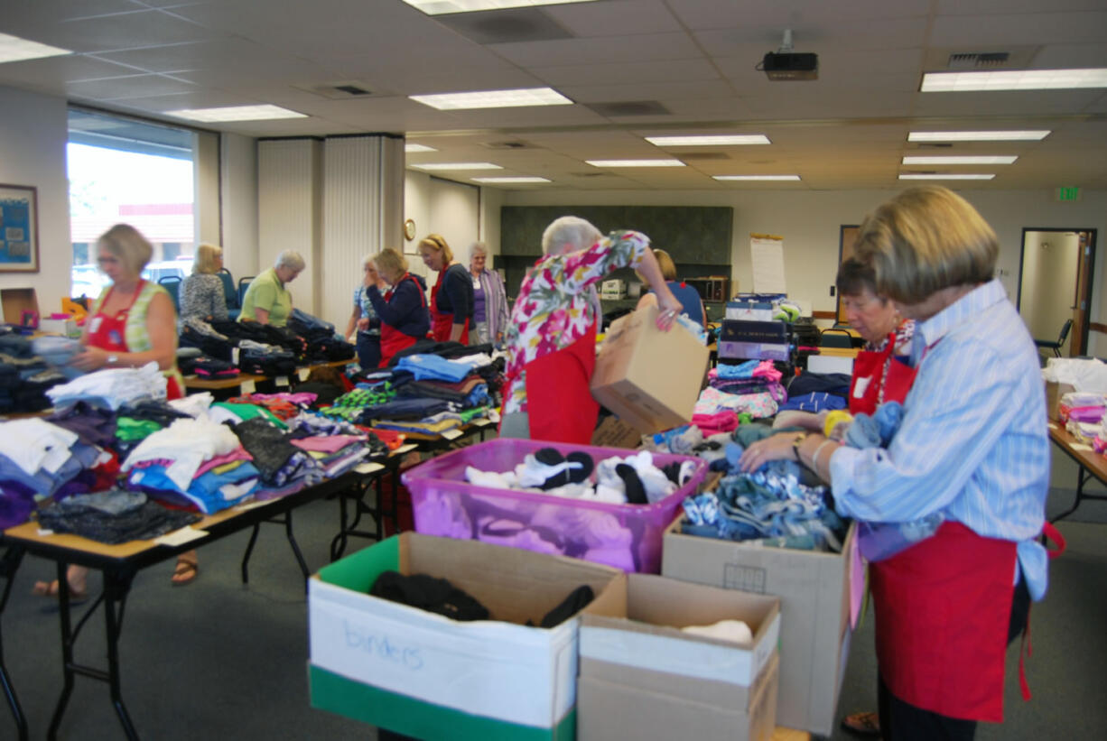 Volunteers with the Assistance League of Southwest Washington work briskly to set up for the &quot;Teen Day&quot; at the Department of Health and Human Services in Vancouver last week. On Thursday, children in foster care were able to attend the event and select two complete outfits in preparation for the start of the new school year.