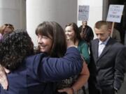 Plaintiff Stephanie McCleary, with her children Kelsey, then 20, and Carter, 15, right, behind, is embraced after a Sept. 3, 2014, hearing at the state Supreme Court in Olympia. Carter was in second grade when his family and others sued the state to adequately fund K-12 education; he is now in 11th grade.
