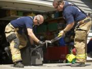 Clark County Fire District 6 firefighters David Fisher, left, and Darren Bush force open a safe July 24 for the Clark-Vancouver Drug Task Force in a search for evidence at the home of a suspected drug dealer.