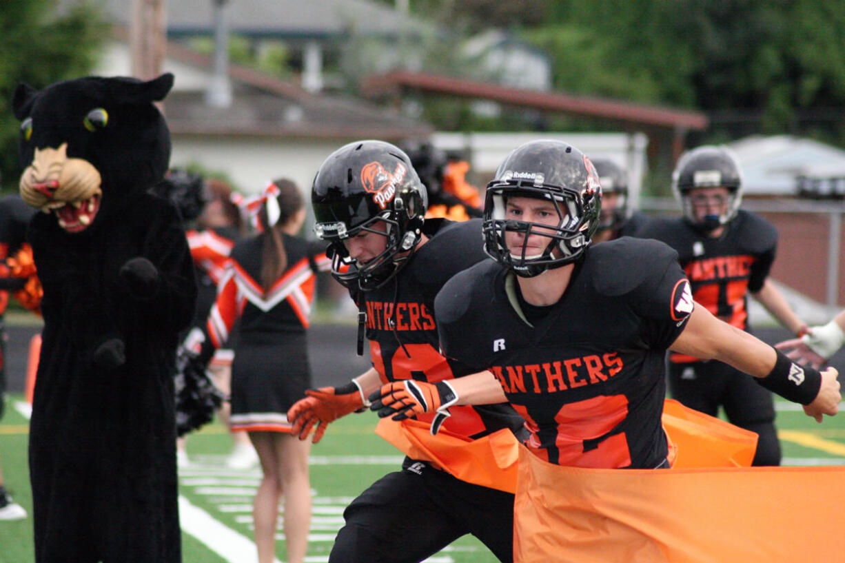 Washougal football players burst through an orange ribbon to celebrate their new turf field at Fishback Stadium.