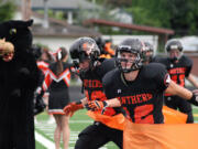 Washougal football players burst through an orange ribbon to celebrate their new turf field at Fishback Stadium.